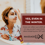 A woman with short, light brown hair applies white sunscreen cream to her face while looking into a mirror. She is wearing a floral patterned robe. Next to her, a text box reads: 'Yes, even in the winter. Snow can reflect up to 80% of UV rays, so don’t even think about skipping your SPF, girl.' The MassageLuXe logo and website URL are displayed below the message, along with a small illustrated sunscreen tube icon."